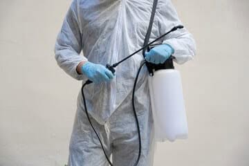 persona in divisa da disinfestatore con attrezzo per disinfestazione in mano